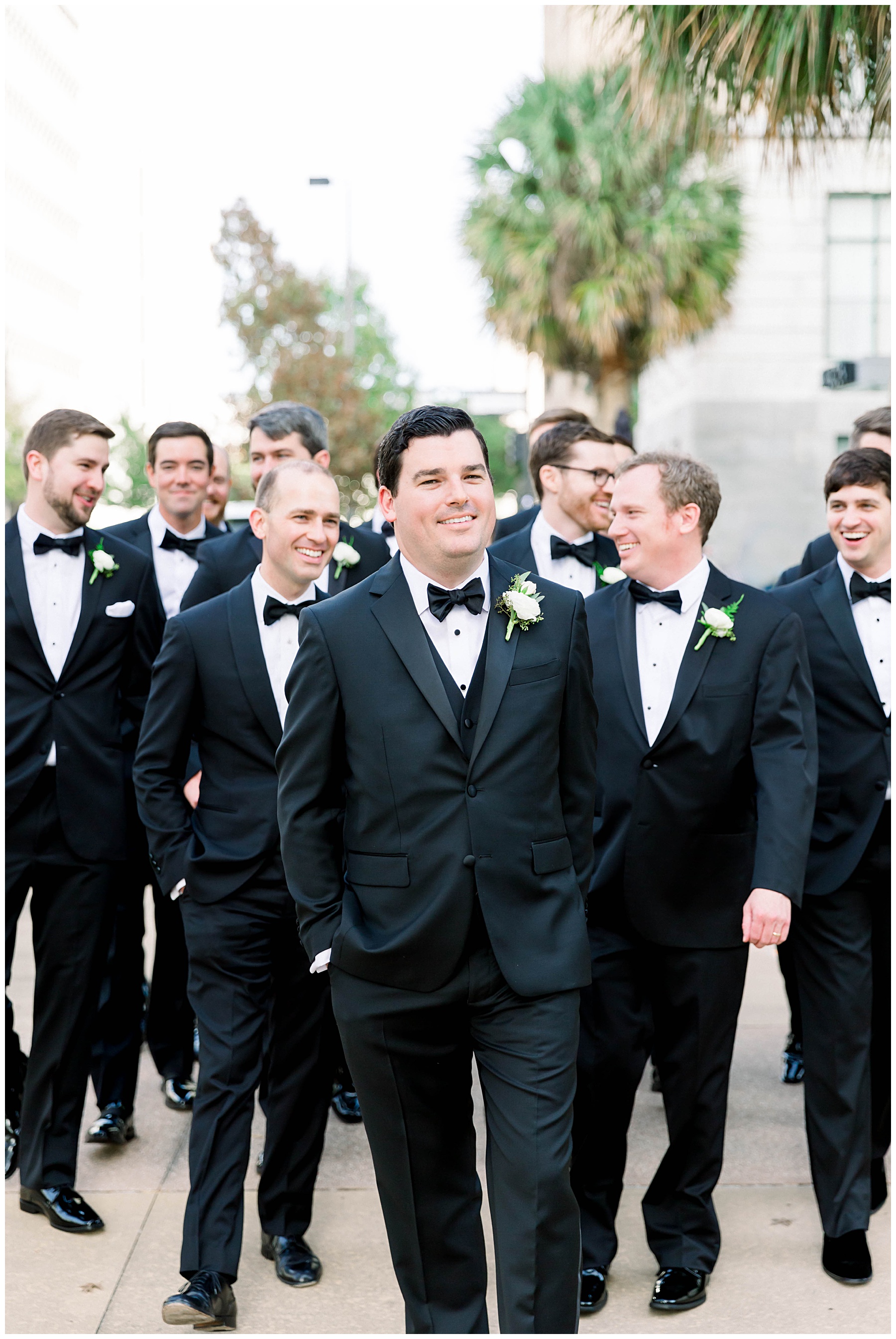 Groom and groomsmen in tuxedos walking and laughing in Downtown Tampa.